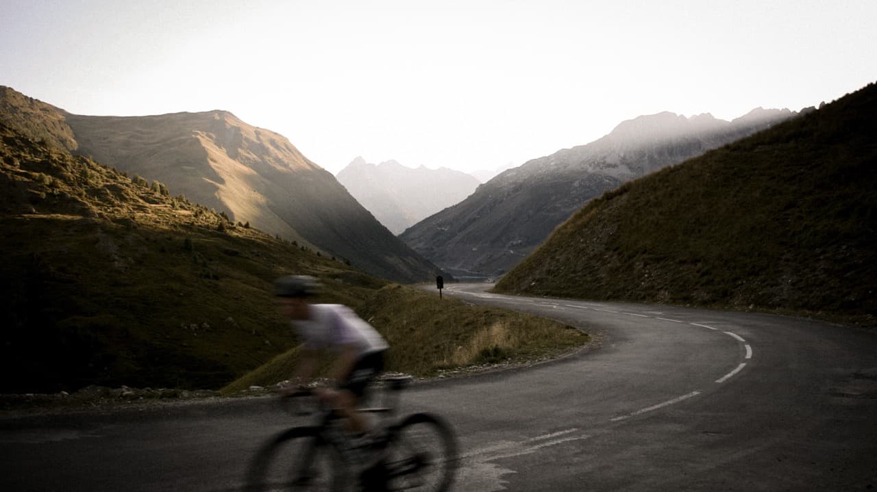 Two cyclists riding on a winding mountain road at golden hour