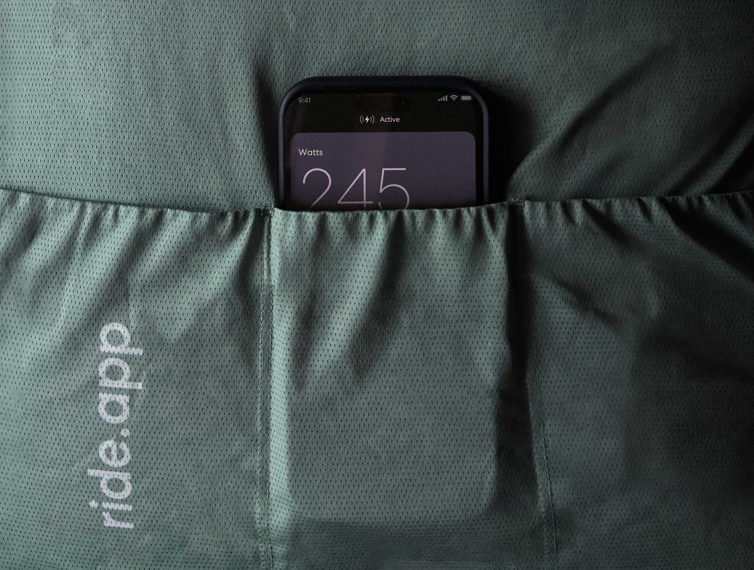 iPhone tucked into a cycling jersey pocket showing live wattage